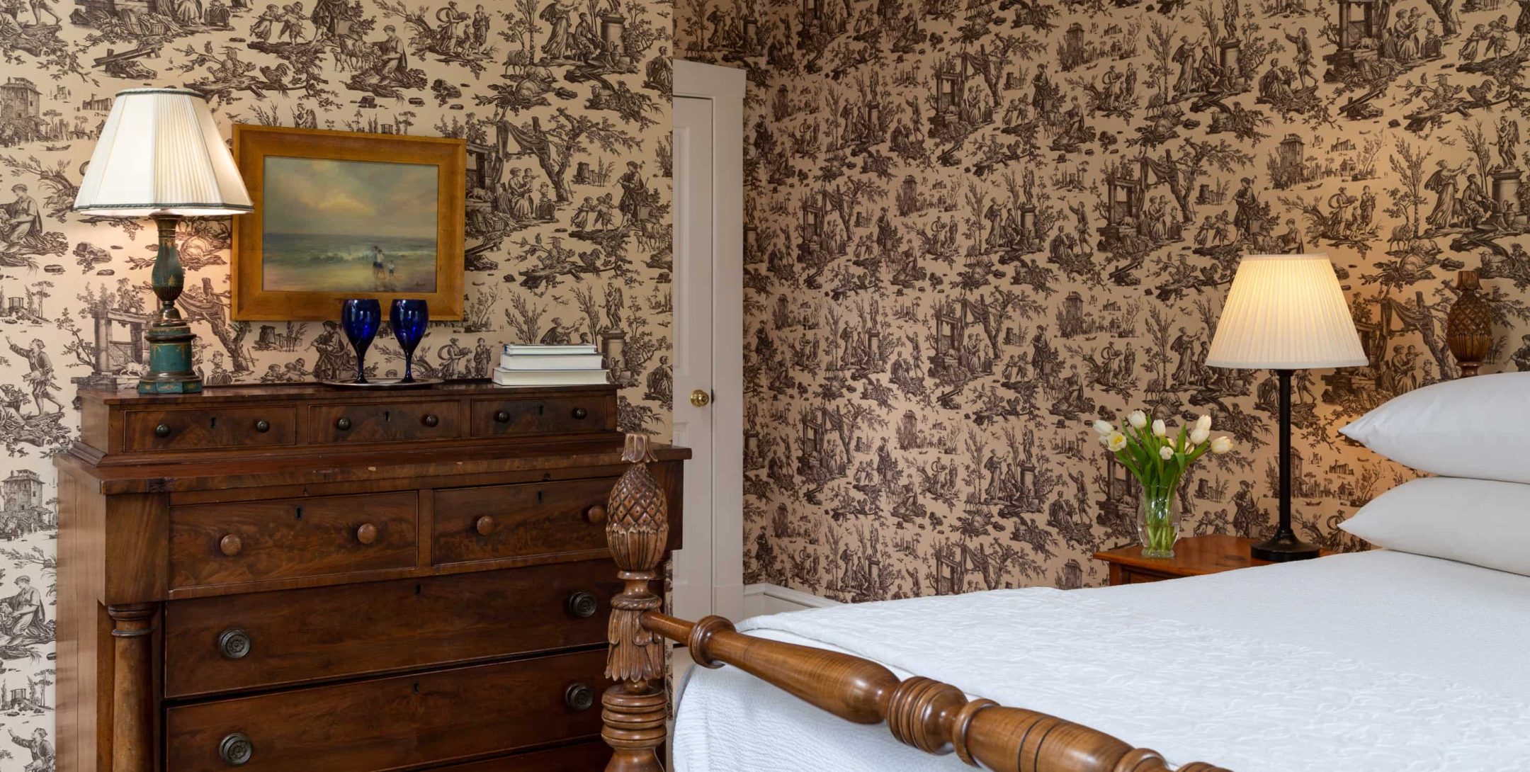 Plush bed, chest of drawers, and flowers in Brown Room at The Inn at Castle Hill