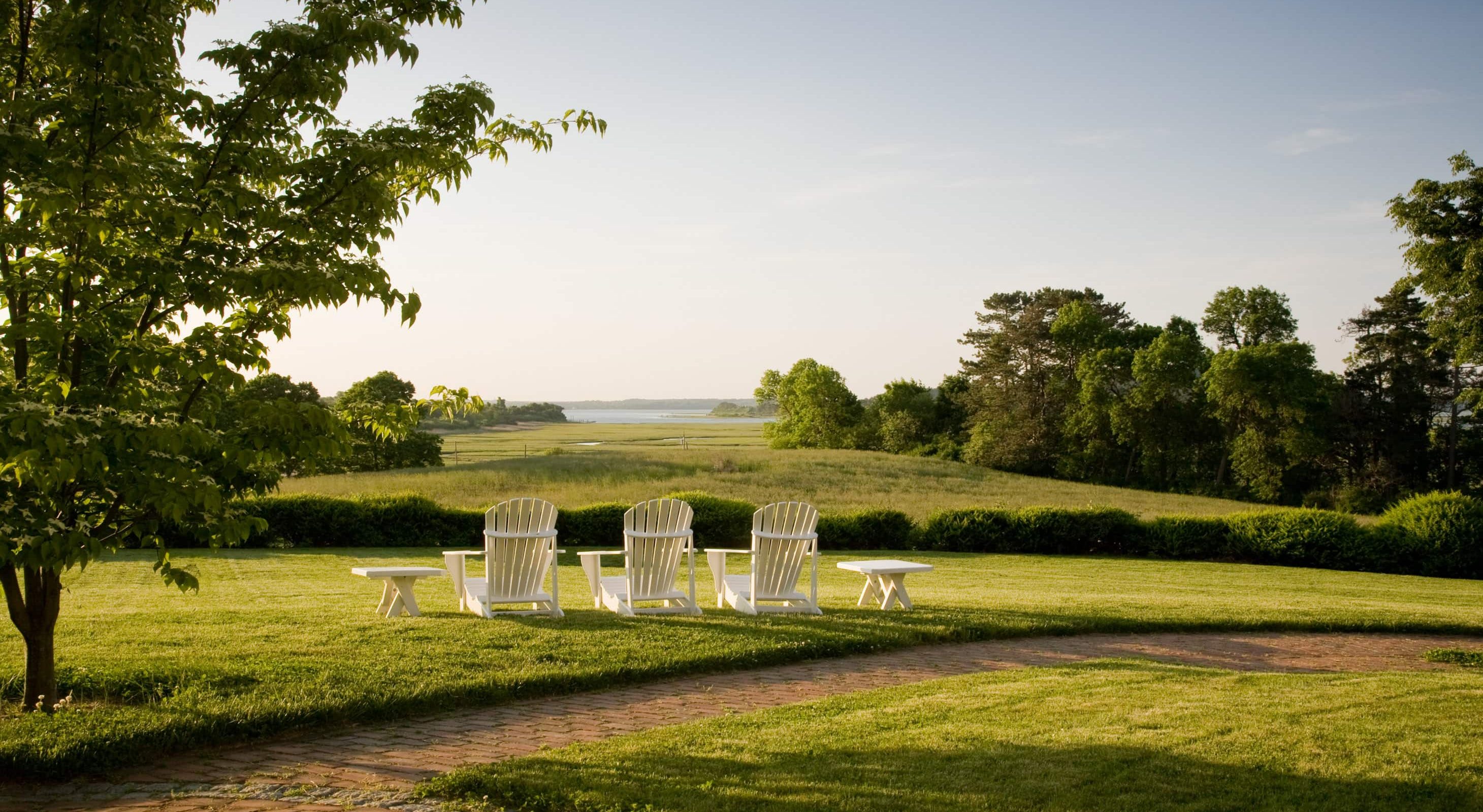 Adirondack chairs in the lawn and a view of the coast at The Inn at Castle Hill