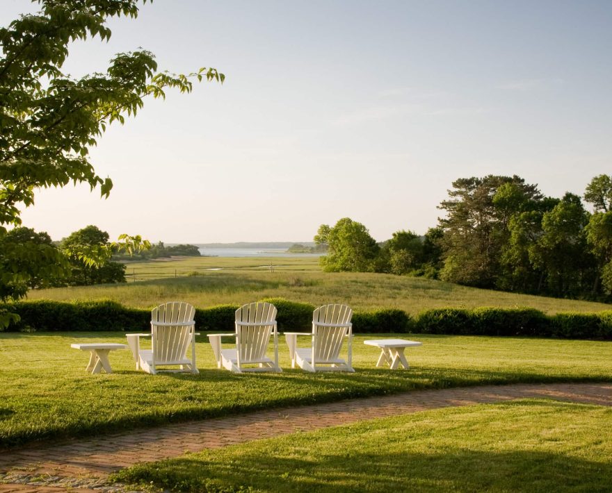 Adirondack chairs in the lawn and a view of the coast at The Inn at Castle Hill