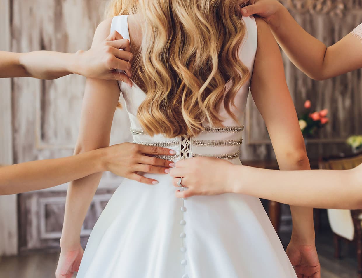 Bridal party helping the bride dress on her wedding day
